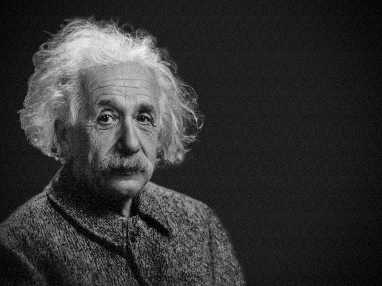 Black and white portrait of Albert Einstein with his signature wild hair, looking directly at the camera with a thoughtful expression.