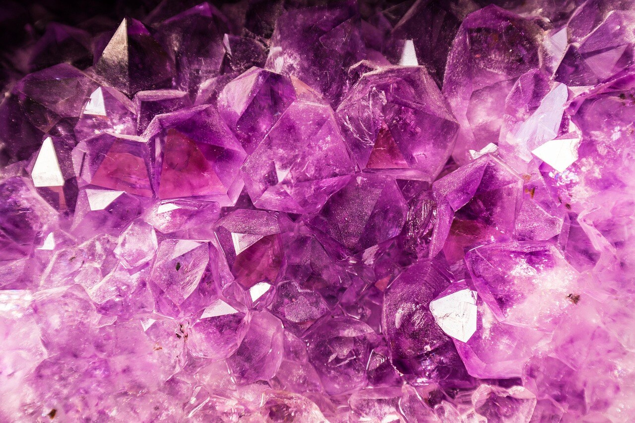 Amethyst crystal cluster with vibrant purple hues and multiple sharp, transparent facets.